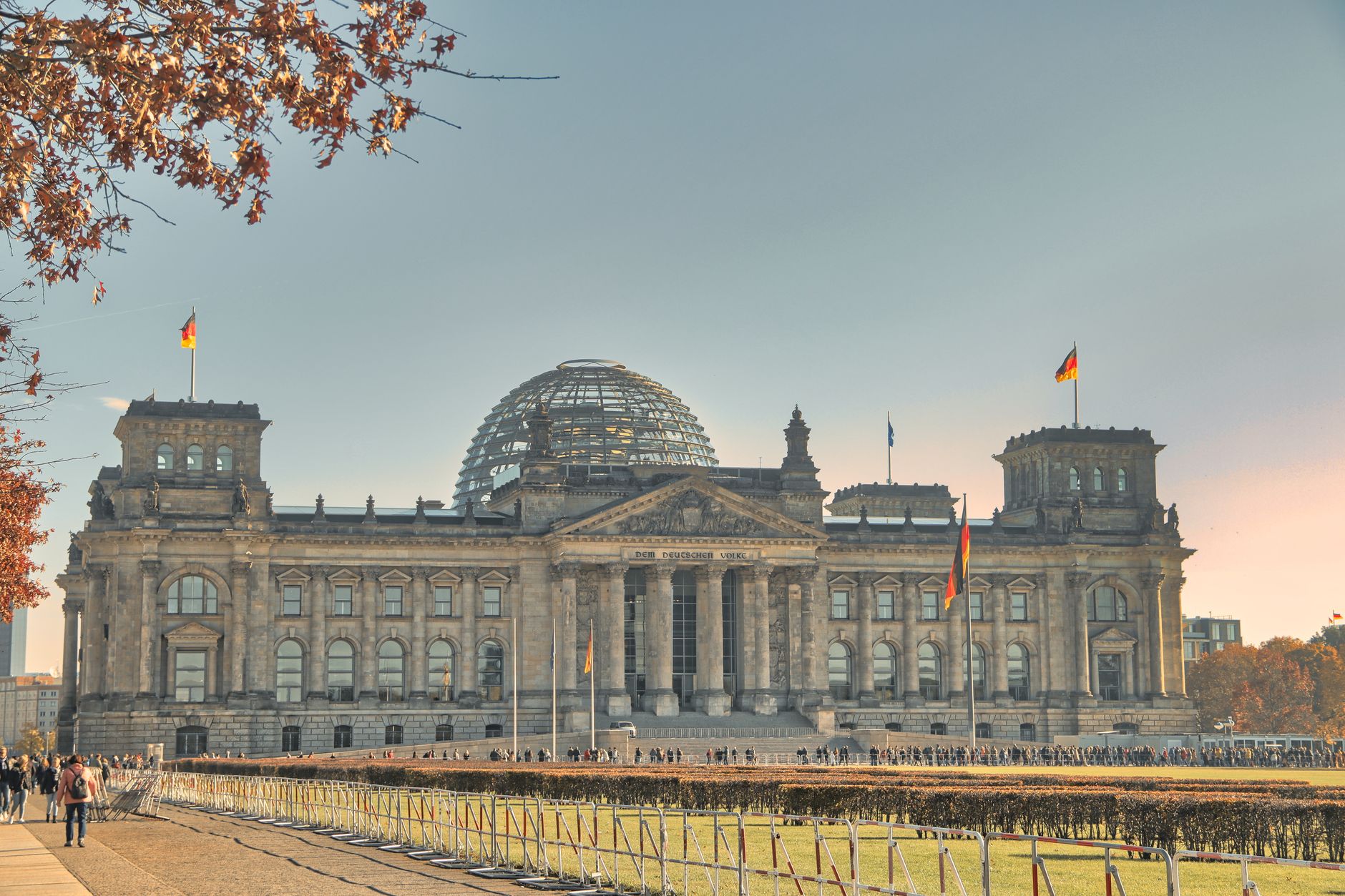 Das historische Reichstagsgebäude in Berlin, Deutschland, mit einer Glaskuppel und herbstlichen Blättern.
