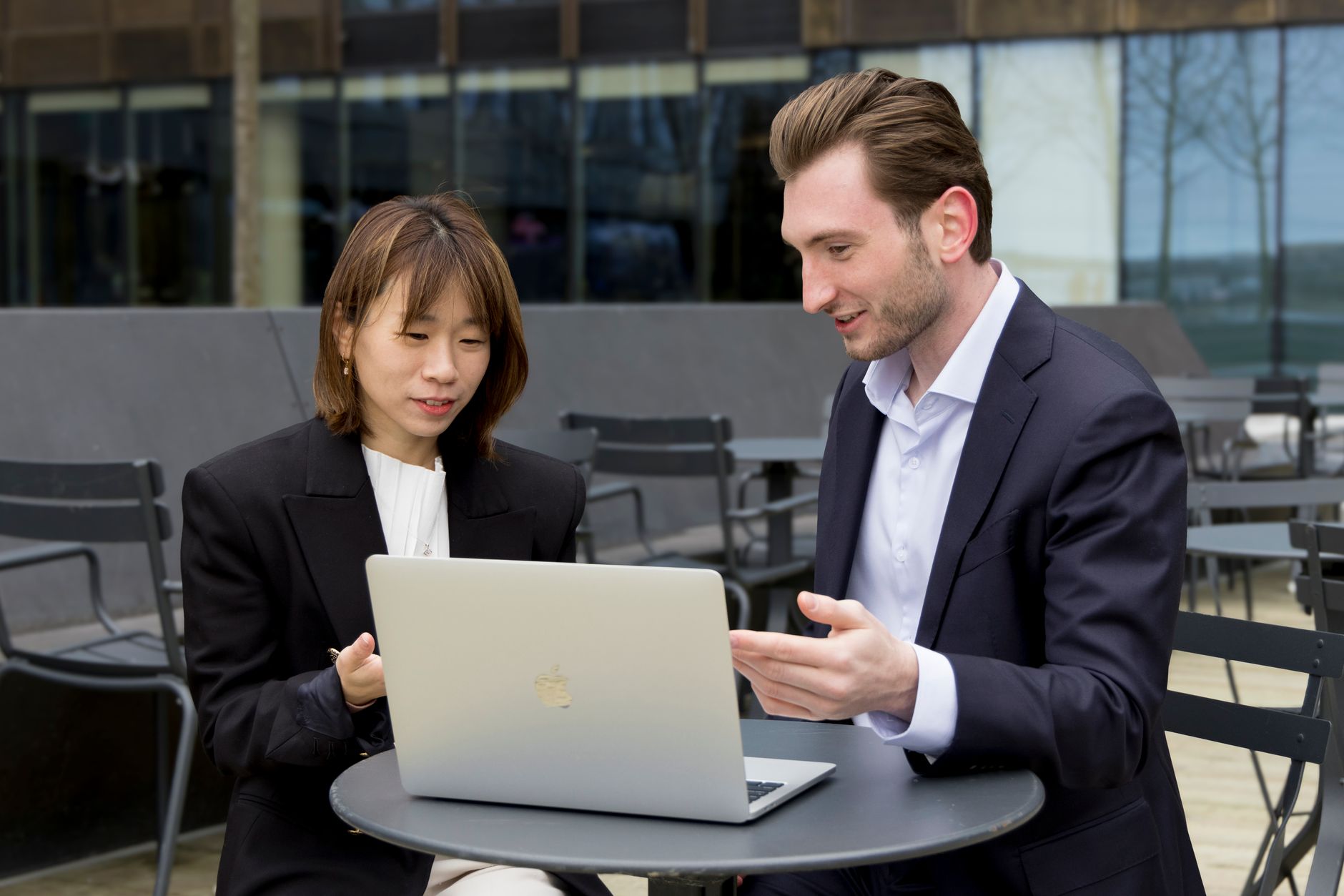 Zwei Fachleute arbeiten über einen Laptop während eines Geschäftstreffens im Freien zusammen.