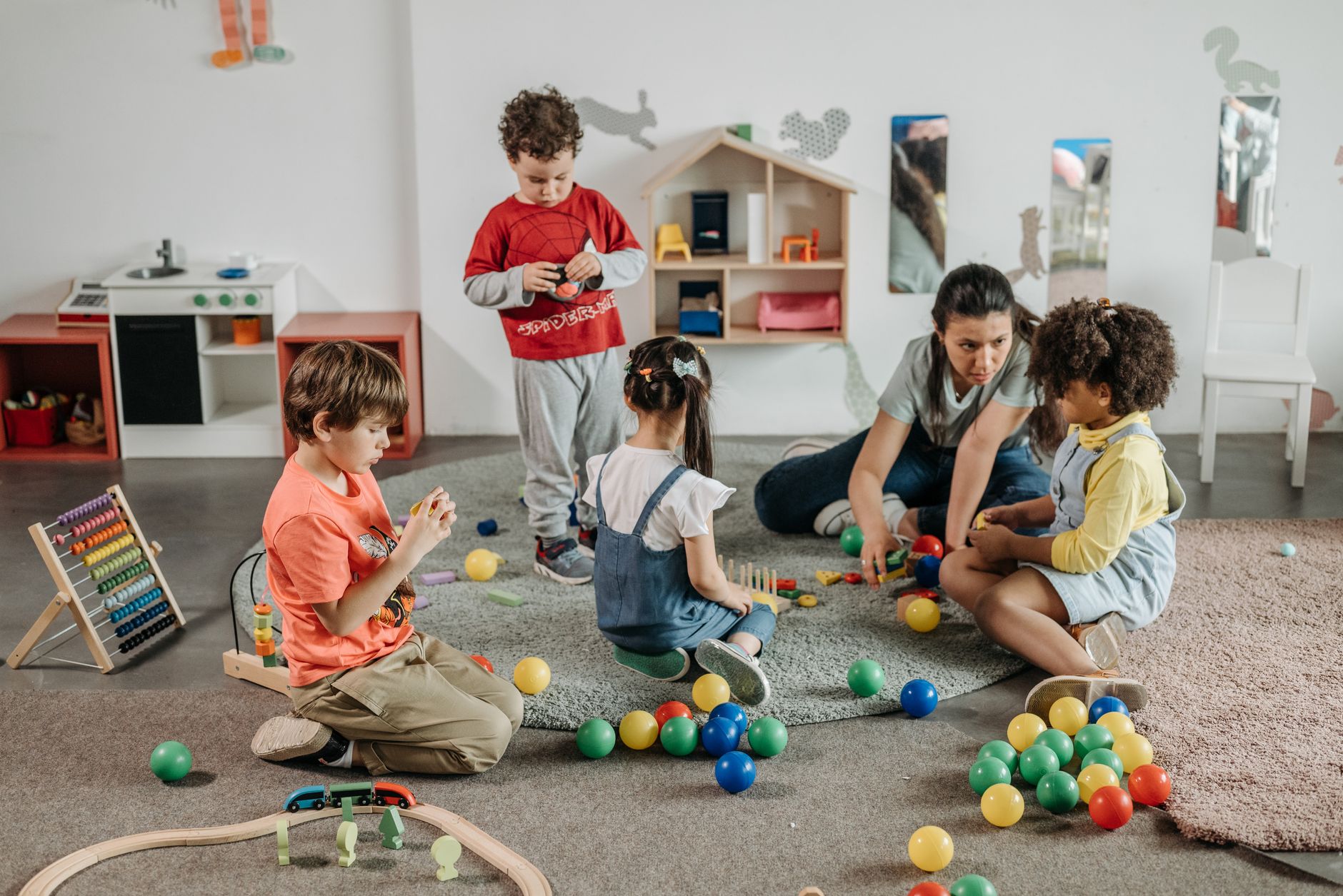 Junge Kinder und ein Lehrer, die in einer Vorschulumgebung an Spiel- und Lernaktivitäten teilnehmen.