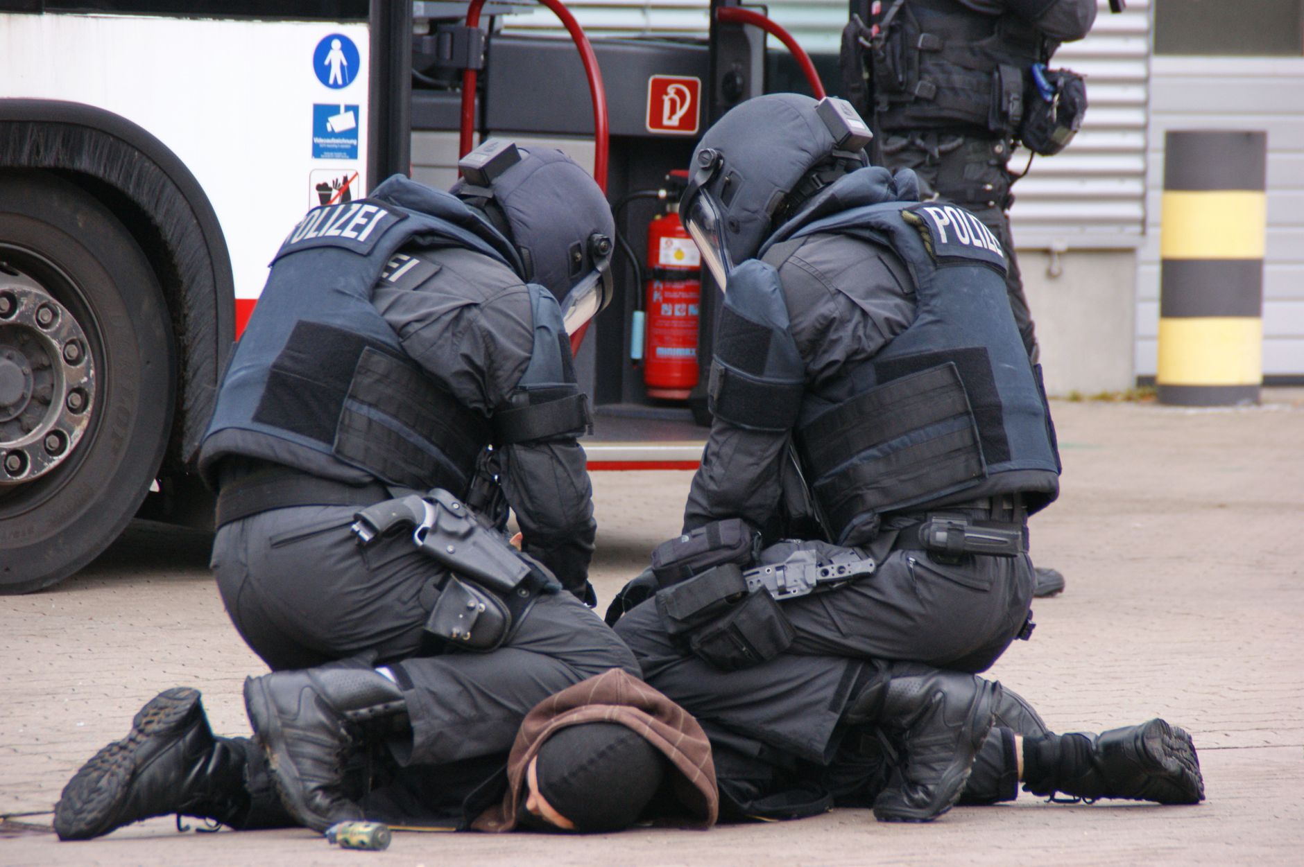 Deutsche Polizisten in voller Ausrüstung nehmen einen Verdächtigen in einem städtischen Gebiet in Hamburg fest.