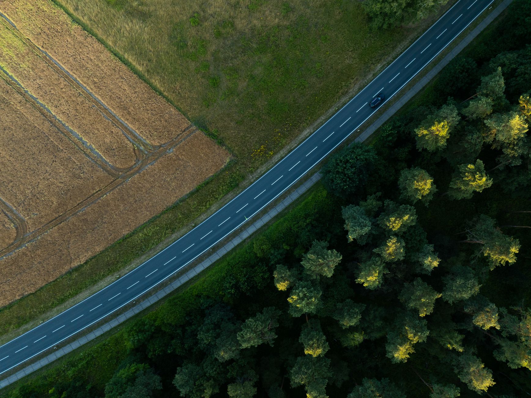 Eine malerische Luftaufnahme, die eine Straße zeigt, die durch Felder und Wald in Königslutter, Deutschland führt.