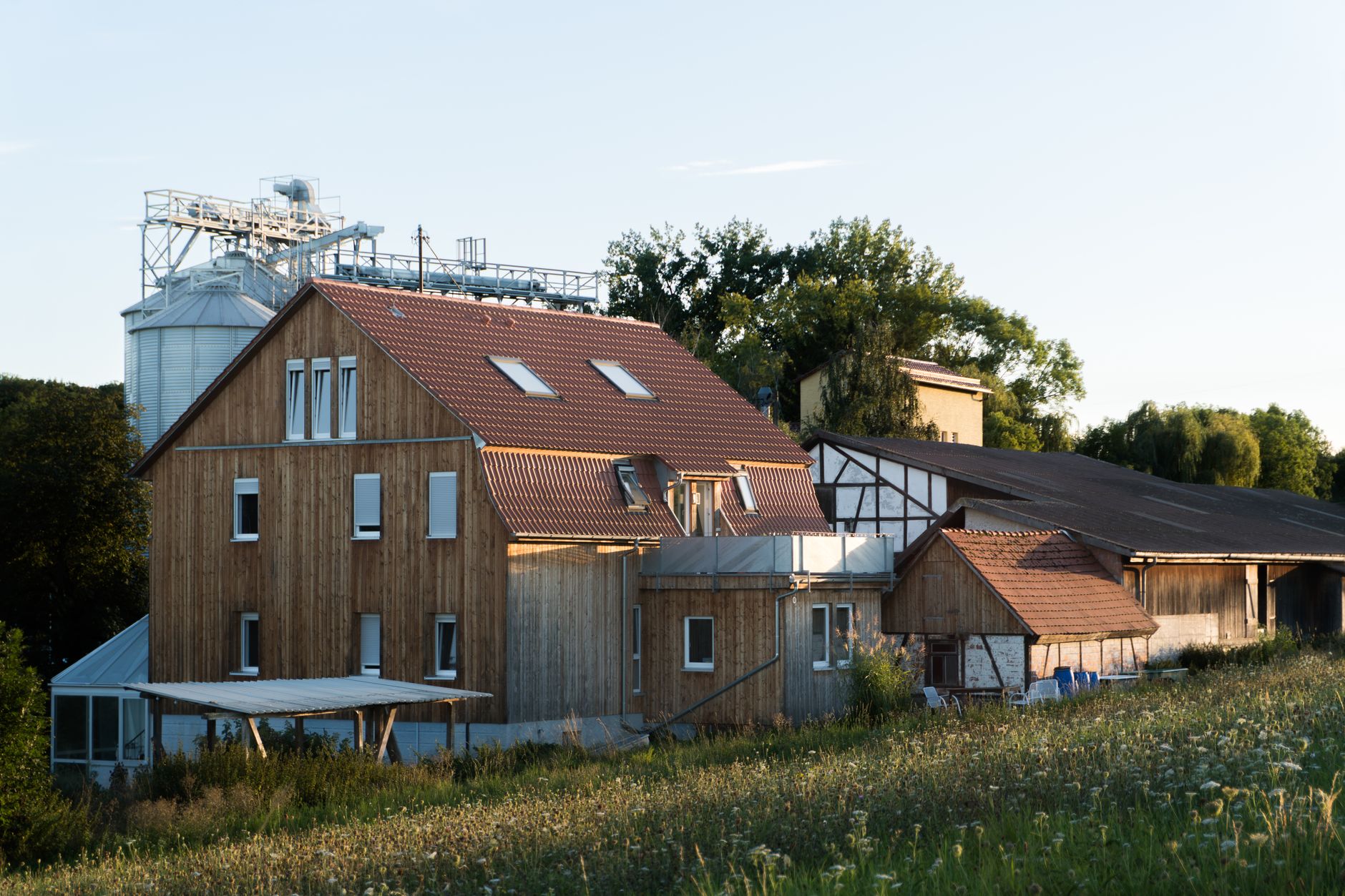 Ein malerisches Bauernhaus aus Holz in ländlicher Umgebung bei Sonnenuntergang.