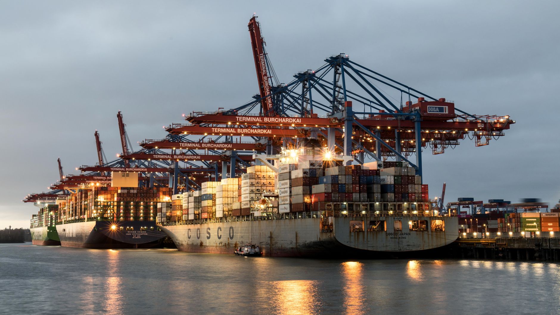 Containerschiffe liegen im Burchardkai-Terminal in Hamburg während der Dämmerung und zeigen reges maritimes Treiben.