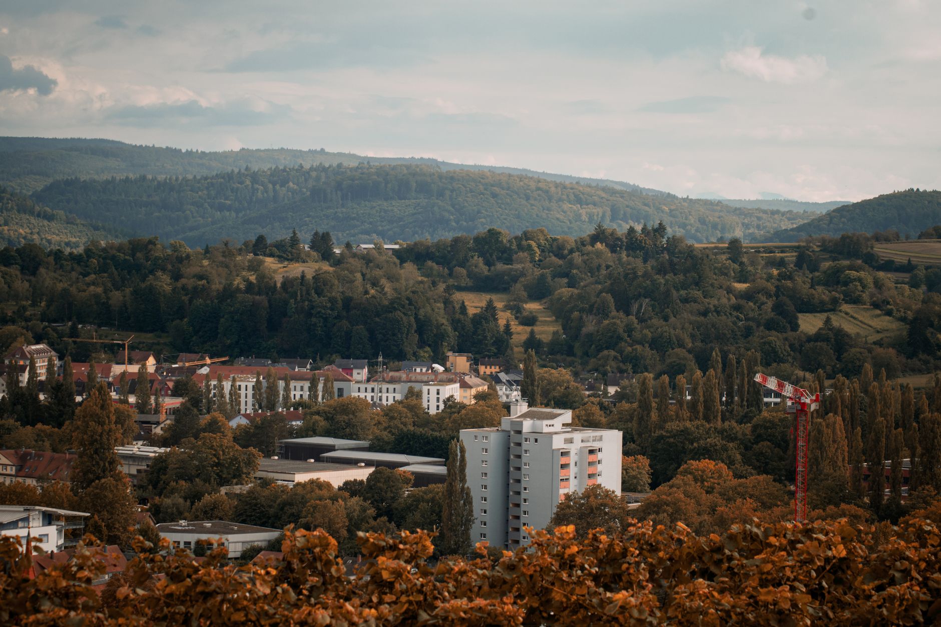 Charmante Herbstlandschaft einer kleinen deutschen Stadt, umgeben von üppigen Wäldern und Bergen.
