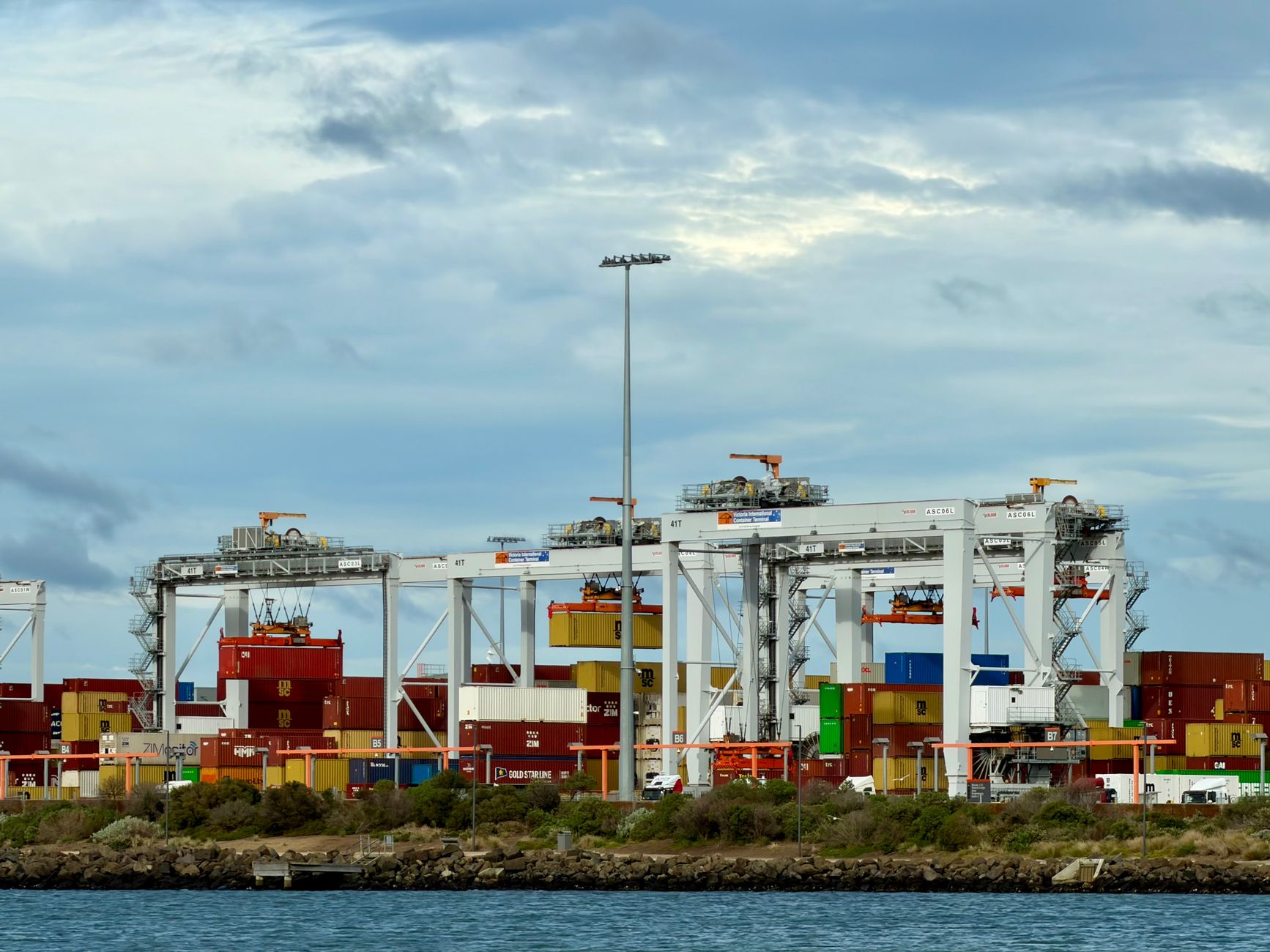 Ein eindrucksvolles Bild eines automatisierten Containerterminals im Hafen von Melbourne, Victoria, das die industrielle Güterabfertigung veranschaulicht.