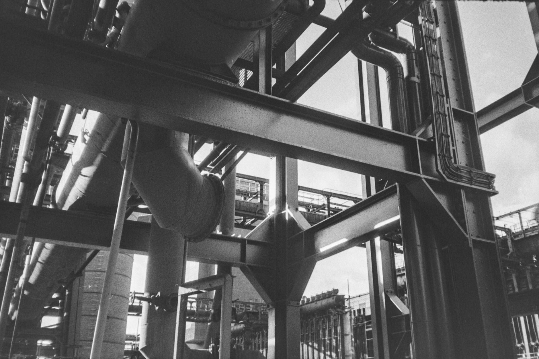 Eine eindrucksvolle Schwarz-Weiß-Aufnahme von komplexen Industrierohren und Metallkonstruktionen.