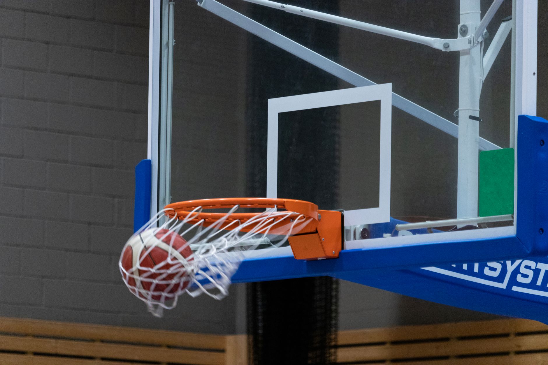 Nahaufnahme eines Basketballspielers, der in einer Indoor-Spielhalle einen Korb erzielt.