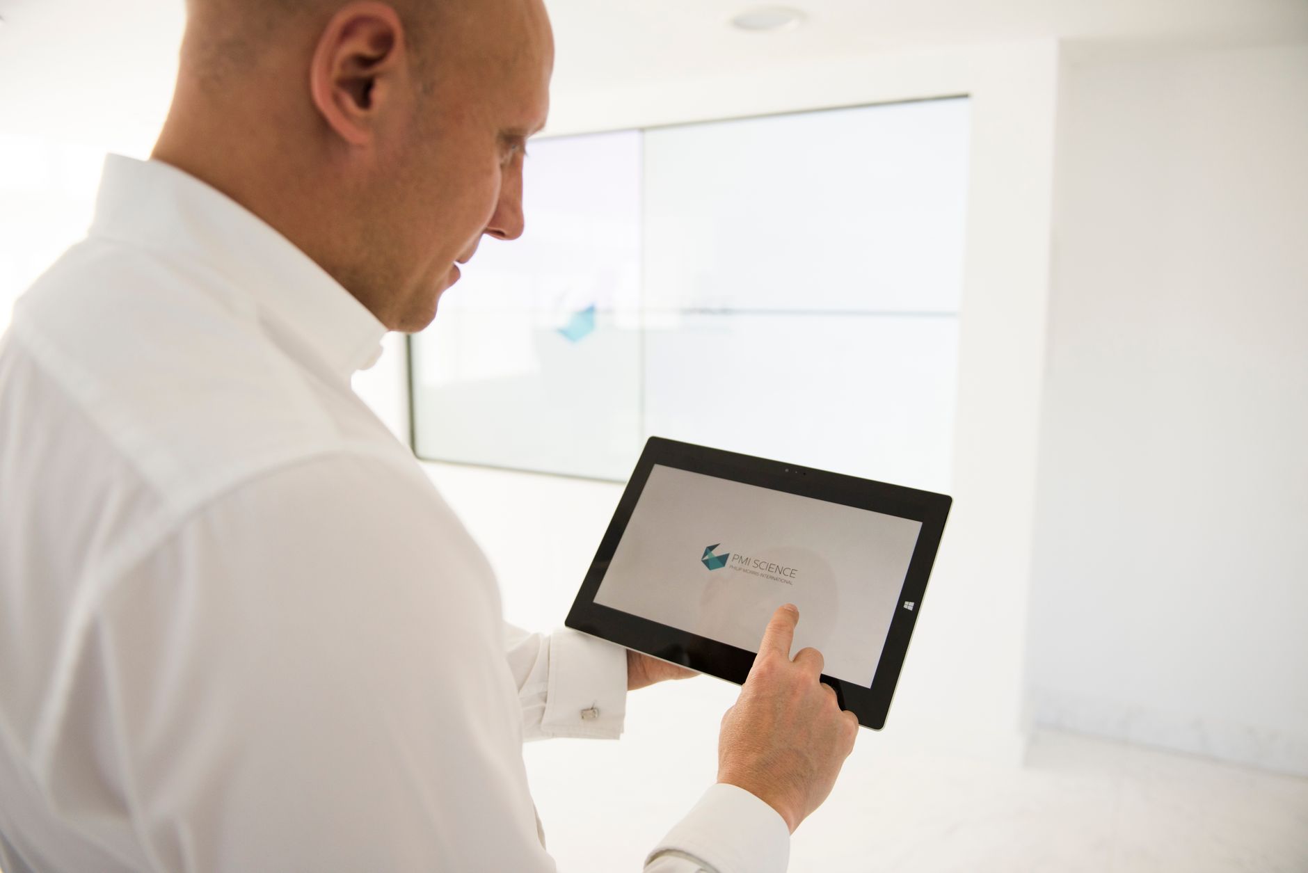 Ein gut gekleideter Geschäftsmann nutzt ein Tablet in einer modernen Büroumgebung.