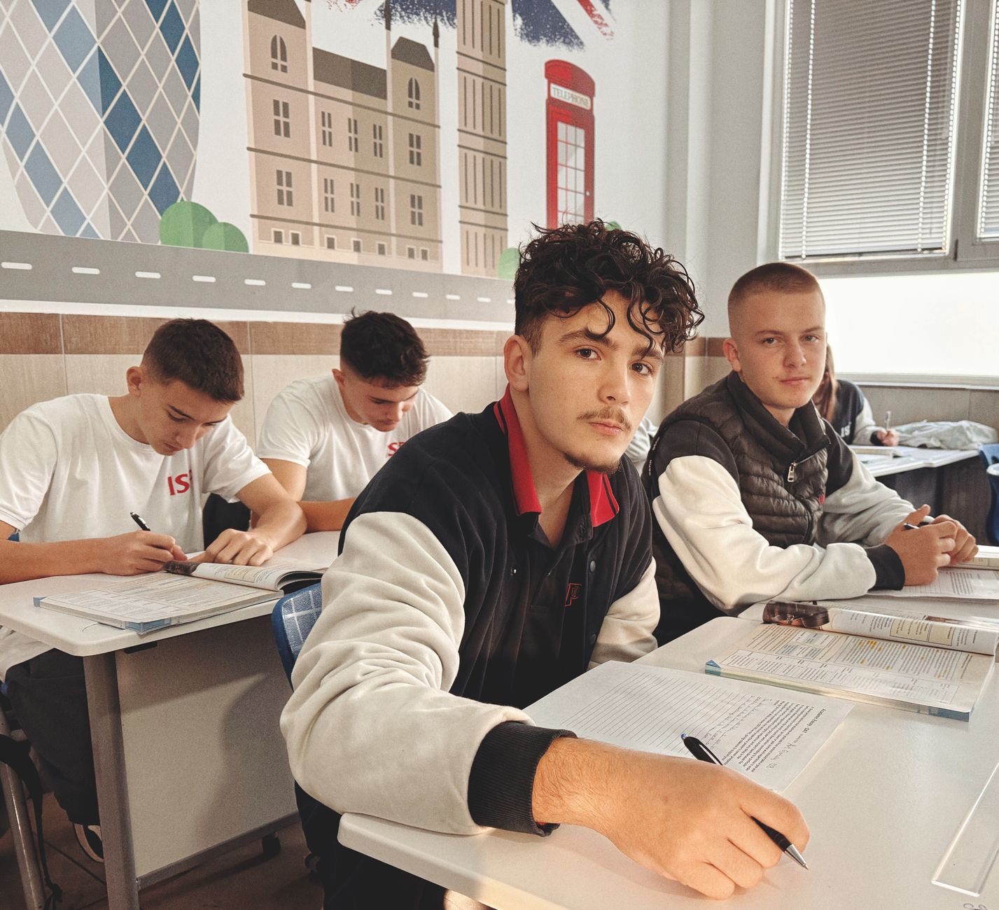 Highschool-Schüler lernen in einem Klassenzimmer mit Wandkunst mit britischen Motiven.
