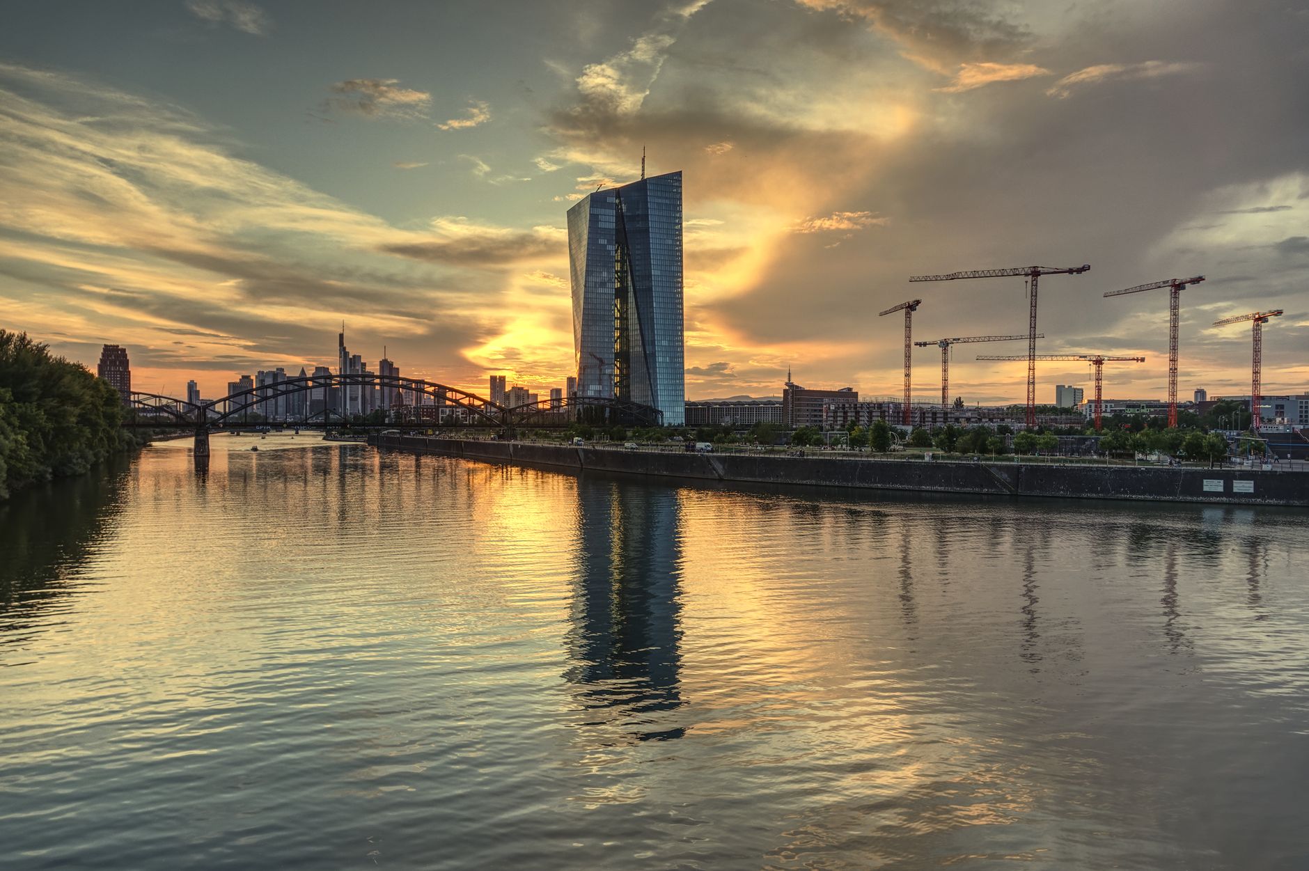 Atemberaubender Blick auf die Frankfurter Skyline und das EZB-Gebäude bei Sonnenuntergang, das sich im Main spiegelt.