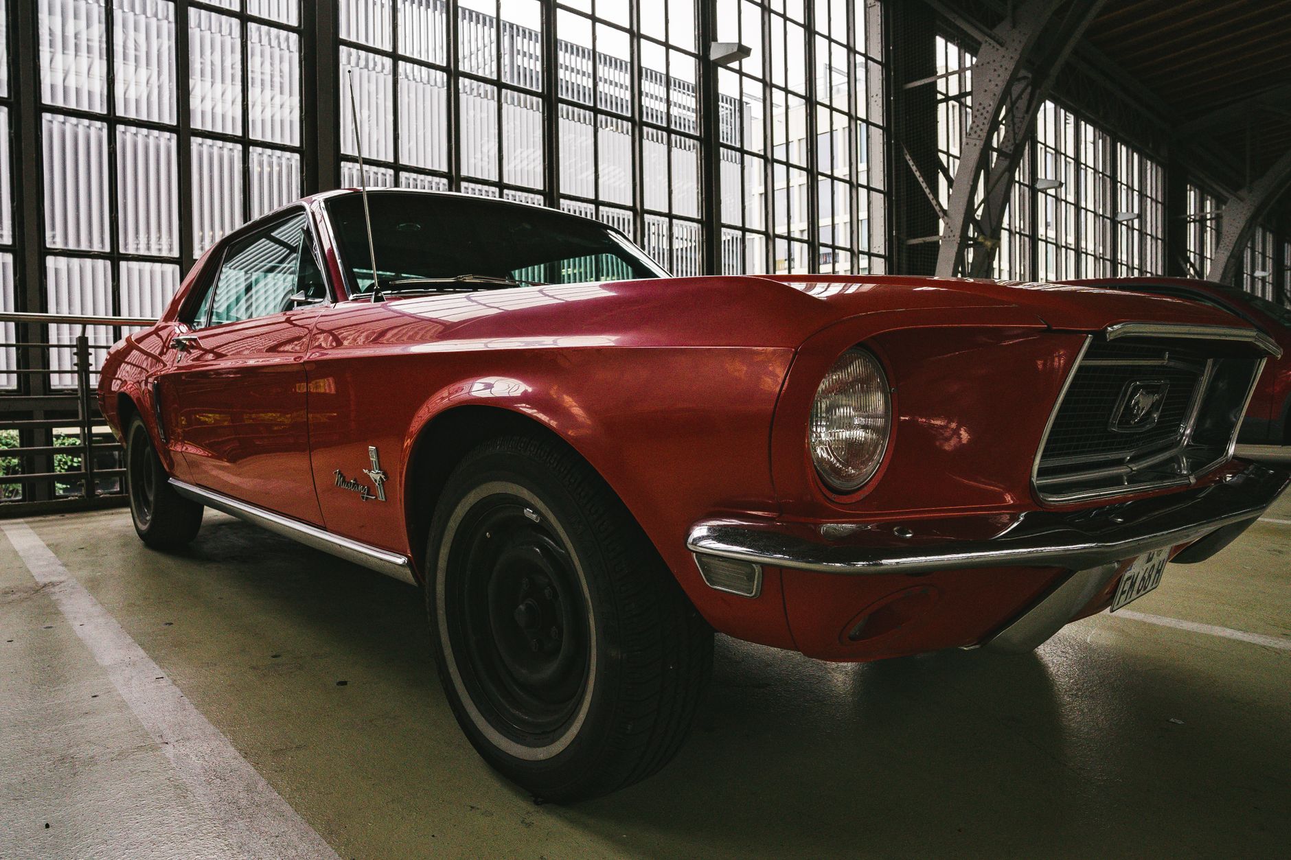 Nahaufnahme eines klassischen roten Ford Mustang, der in einer städtischen Garage parkt.