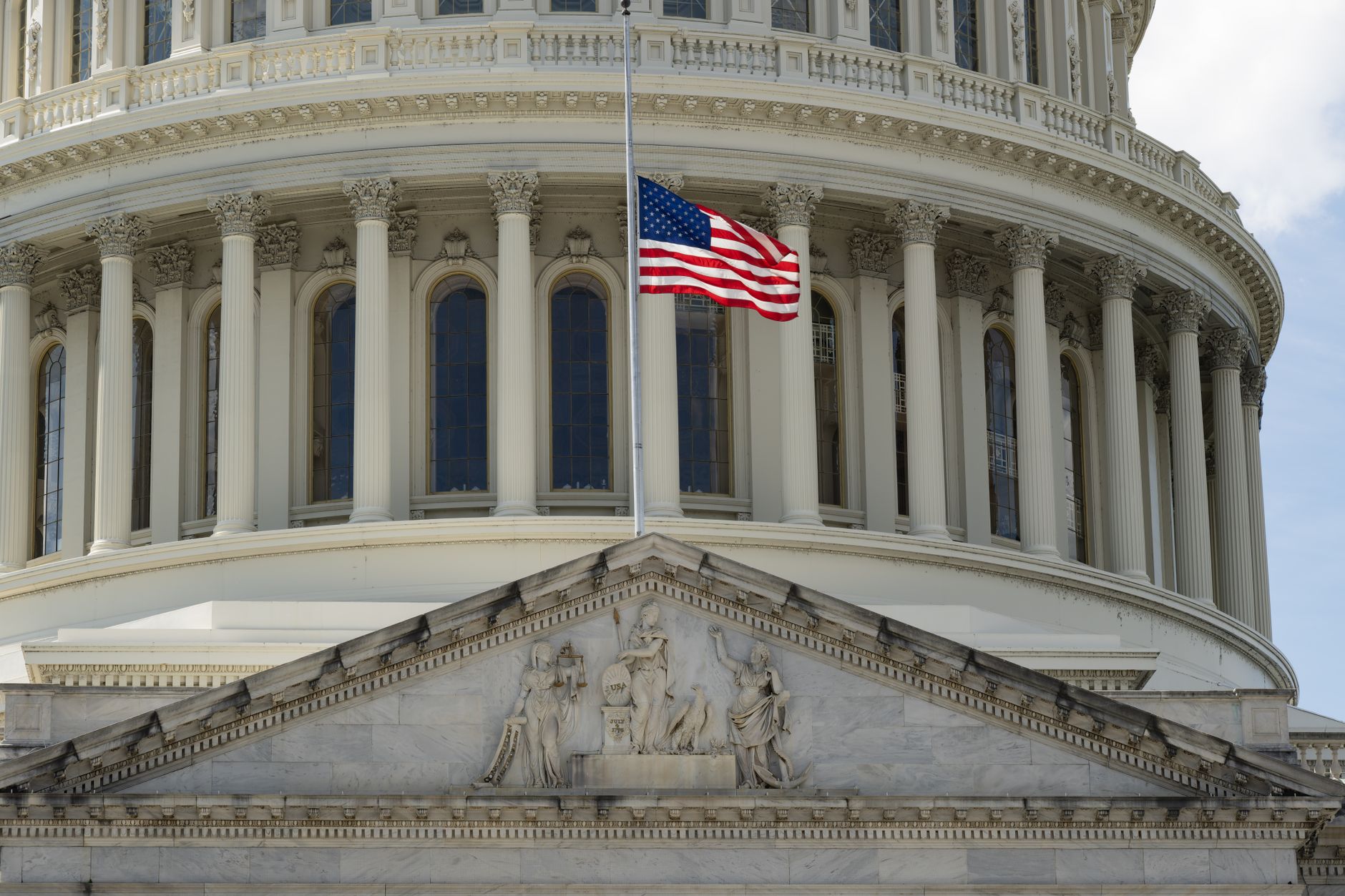 Nahaufnahme des Kapitols in Washington DC mit der wehenden US-Flagge davor.