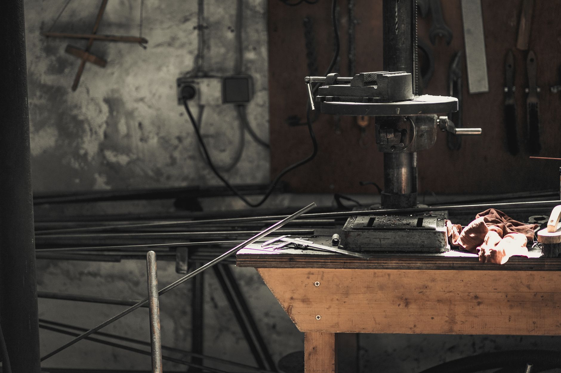Eine detaillierte Ansicht einer Metallwerkstatt, die Werkzeuge, Maschinen und Stahlstangen zeigt.
