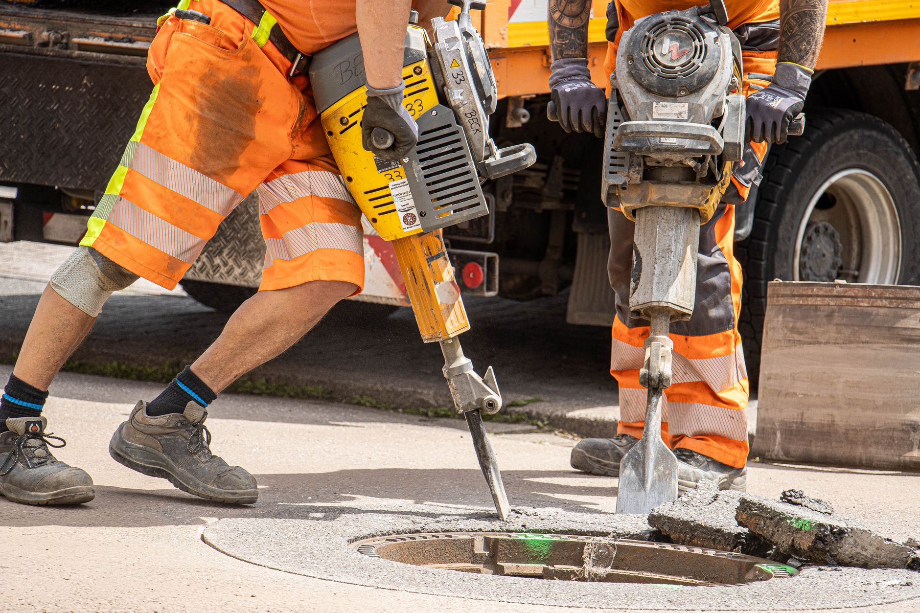 Bauarbeiter reparieren Straßen mit schwerem Werkzeug und betonen die Stadtentwicklung.