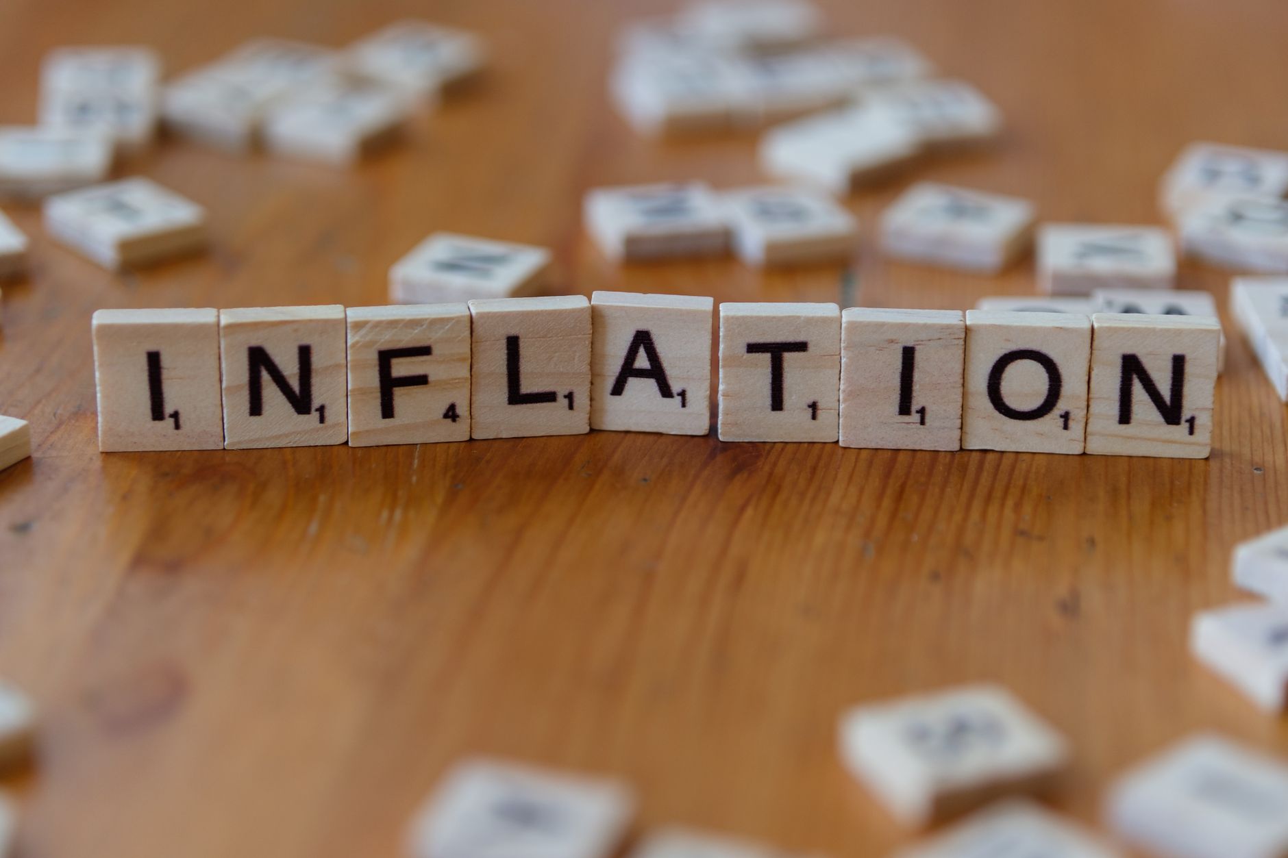 Scrabble-Buchstabensteine mit der Schreibweise „INFLATION“ auf einem Holztisch stehen für wirtschaftliche Konzepte.
