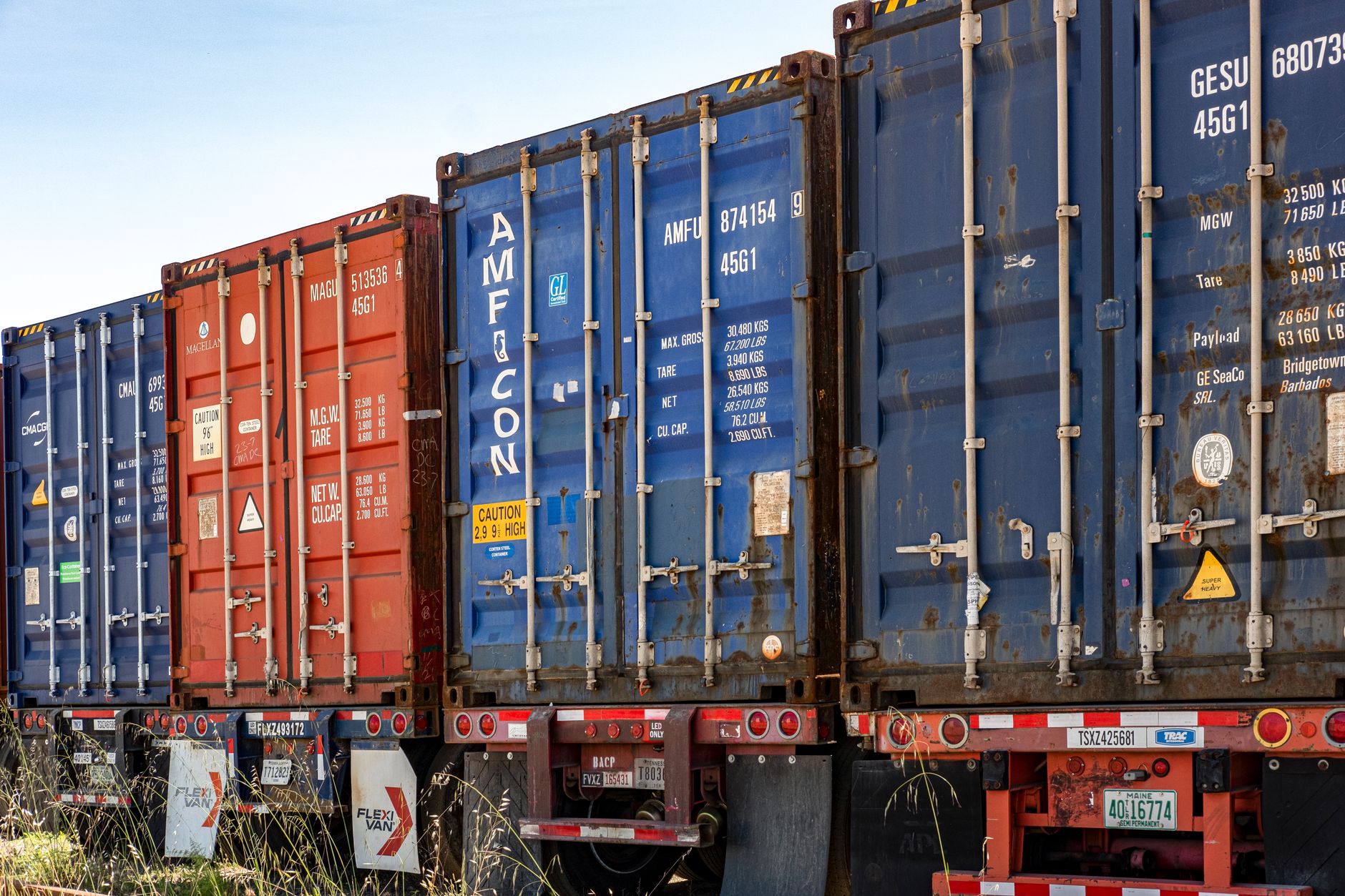 Reihe bunter Frachtcontainer in einem industriellen Versandhof, bereit für den Transport.