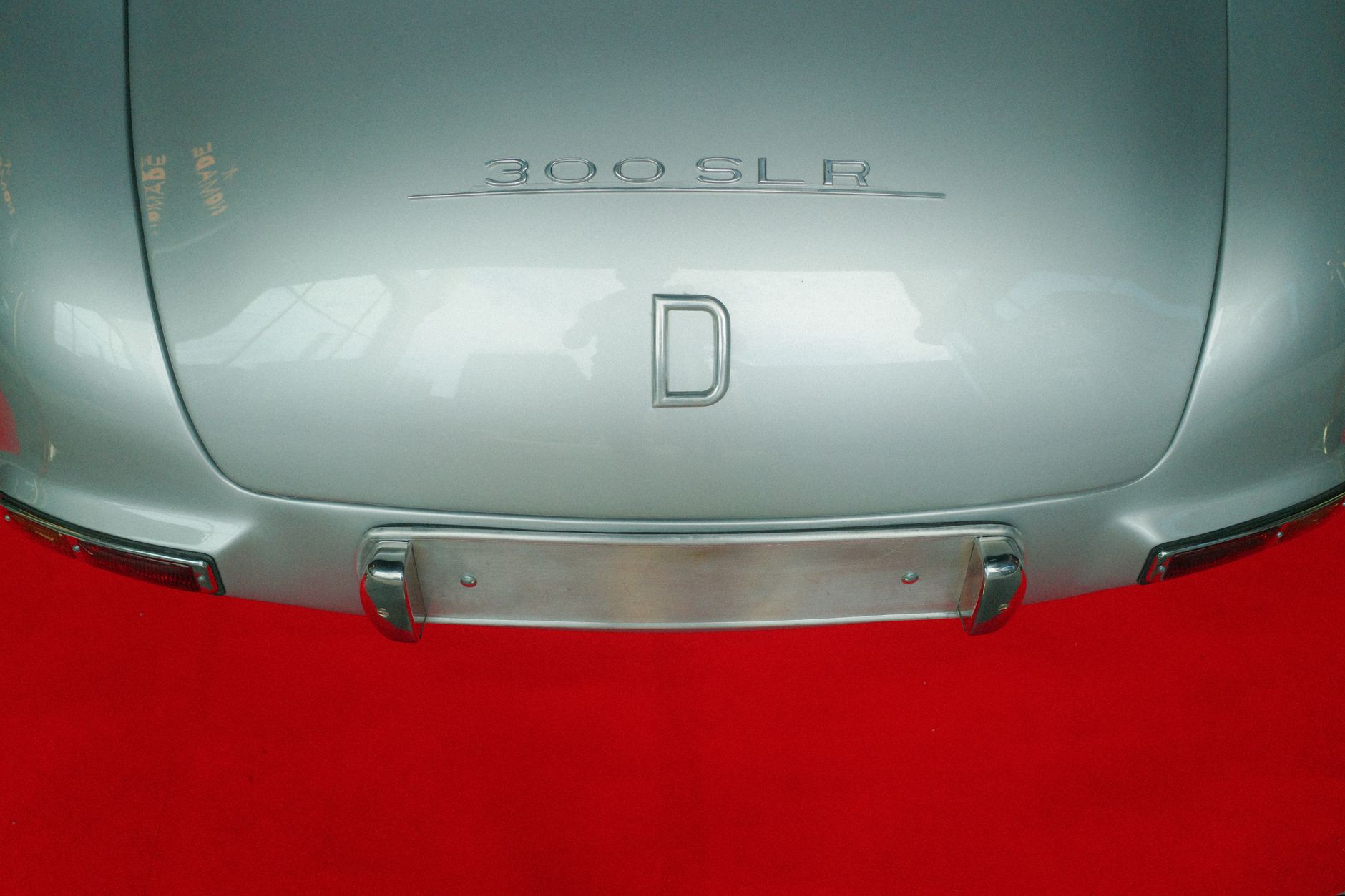 Nahaufnahme der Rückansicht eines klassischen 300 SLR Autos auf einem lebhaften roten Teppich, was Eleganz und Luxus betont.