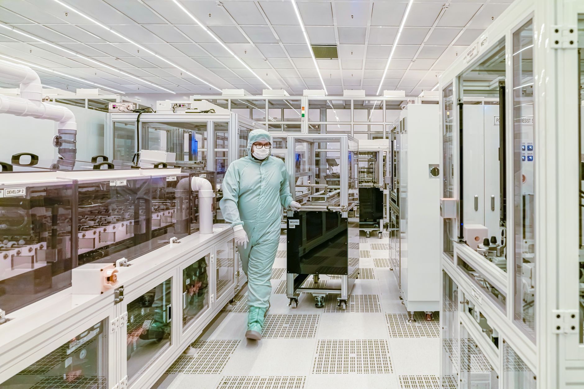 Wissenschaftler in Schutzausrüstung, der in einer hochmodernen Reinraumlaborumgebung geht.